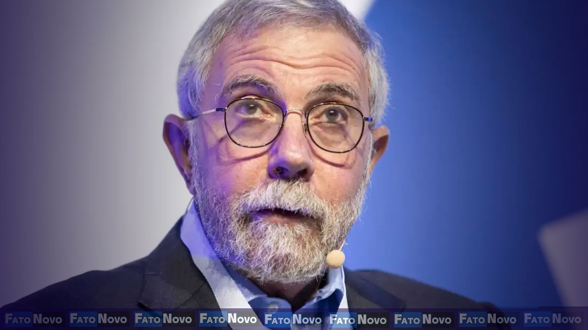 "Imagem de Paul Krugman em evento público, economista olha para a câmera com expressão crítica."